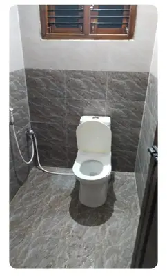 a bathroom with a white toilet in a room at Friendly homestay in Mysore