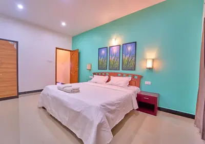 a bedroom with a large white bed with blue walls at Pine Forest View Ooty by VOYE HOMES in Ooty