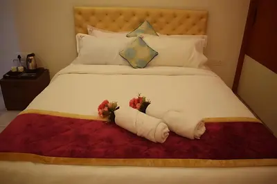 a bed with white sheets and flowers on it at Broadway Inn in Mysore