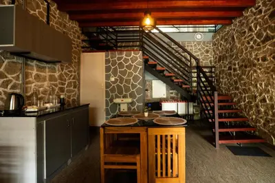 a kitchen with a table and a spiral staircase at Villa La Vista Homestay in Calicut