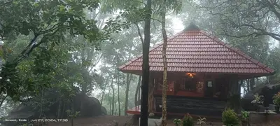a small house with a red roof in a forest at Naturia in Ambalavayal
