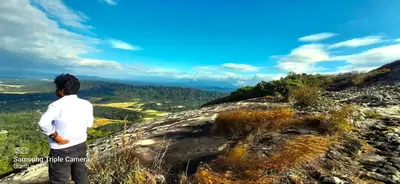 a man standing on top of a mountain looking at the valley at Naturia in Ambalavayal