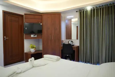 a bedroom with a bed and a desk with a computer at Pearl Residency Kalady in Kāladi