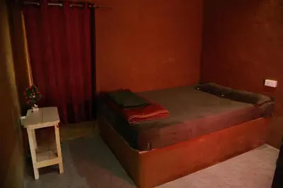 a small bedroom with a bed and a red curtain at Vihara Mudcamp in Marayoor