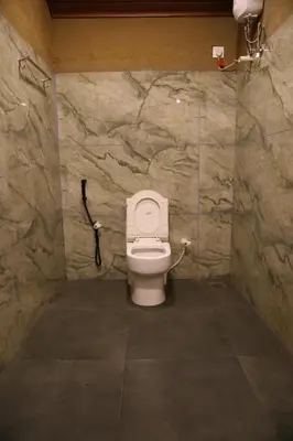 a bathroom with a toilet in a stone wall at Vihara Mudcamp in Marayoor