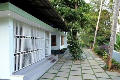 a white house with a pathway leading to it at Malayil Peacock Villa in Wayanad