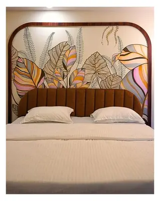 a bed with a floral mural on the wall at Event House, Mysore in Mysore