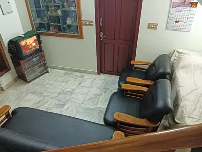 a room with a chair and a bed and a tv at Shield Guest Accommodation in Pudunagaram
