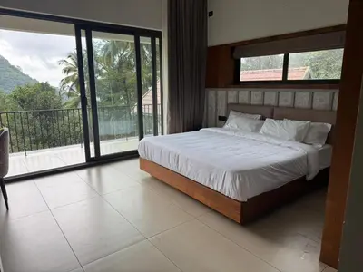 a bedroom with a bed and a large window at GINGY Holidays in Wayanad