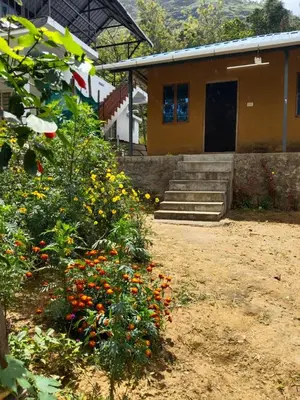 a house with a bunch of flowers in front of it at BREEZE GARDEN MUD HOUSE Home Stay in Kanthalloor