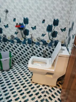 a bathroom with a toilet with blue flowers on the wall at BREEZE GARDEN MUD HOUSE Home Stay in Kanthalloor