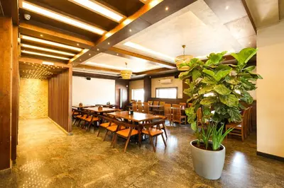a restaurant with wooden tables and chairs and a potted plant at SSR Comforts in Mandya