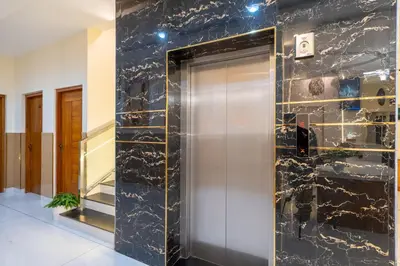 a elevator in a lobby with a black marble wall at Victoria Suites Airport Hotel in Nedumbassery