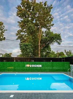 a blue swimming pool in front of a fence at Victoria Suites Airport Hotel in Nedumbassery
