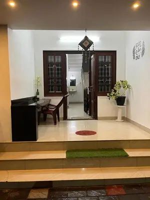 a living room with a table and a clock on the wall at Garden view home stay for family near meitra hospital in Kozhikode