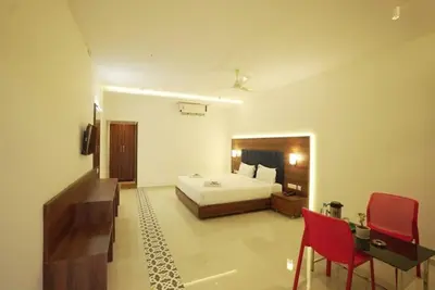 a bedroom with a bed and a desk and red chairs at Kamath Village Resortz