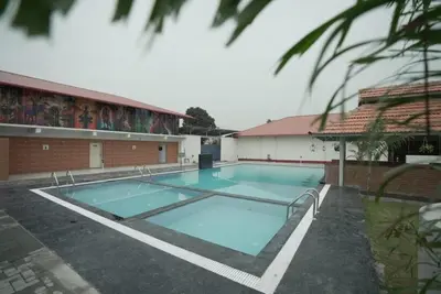 a large swimming pool in front of a building at Kamath Village Resortz