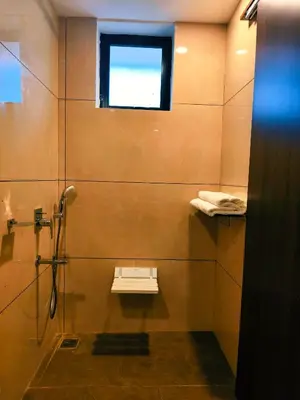 a bathroom with a shower with a sink and a window at Parays Fernwoods in Mannārakkāt