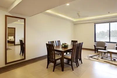 a dining room with a table and chairs and a mirror at Parays Fernwoods in Mannārakkāt