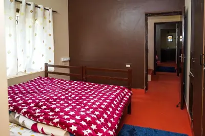 a bedroom with a bed with a red and white blanket at Hertz home in Ooty