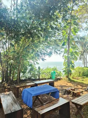 a group of picnic tables with the ocean in the background at Perch by the sea 2 in Kannur