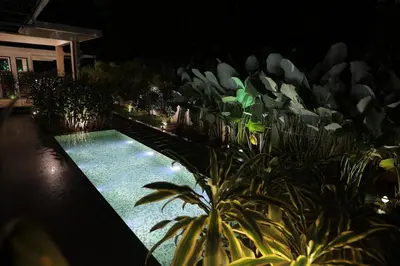 a swimming pool in a garden at night at Mon Reve - Home in the valley in Puthuppādi