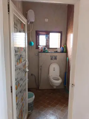 a bathroom with a toilet and a window at Private Room with Kitchen for Decent Couples & Families in Mysore