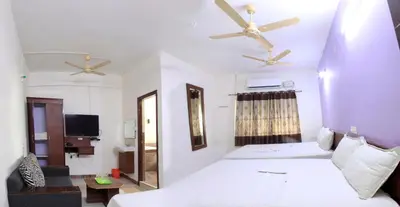 a bedroom with a bed and two ceiling fans at Parva Residency in Palladam