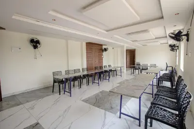 a conference room with tables and chairs and a fan at Parva Residency in Palladam