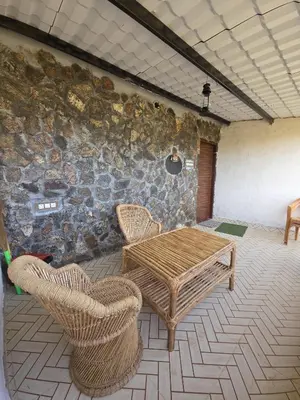 a room with a table and chairs and a stone wall at Rangers Nest Bandipur in Gundlupet