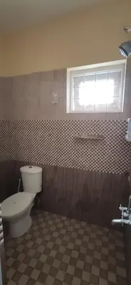 a bathroom with a toilet and a window at Nivriti Cottage Valley View Stay in Ooty