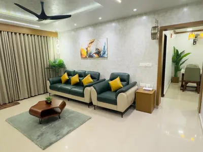 a living room with a blue couch and yellow pillows at Bayfront Bliss - Flat 3BHK in Calicut Beach-Wakeup to stunning views in Kozhikode