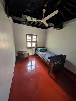 a bedroom with a bed and a ceiling fan at Traditional Kerala house, Thalassery, Kannur in Tellicherry