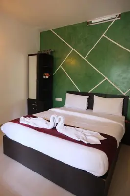 a bedroom with a large bed with a green wall at Skyfall adventure rooms in Meppādi