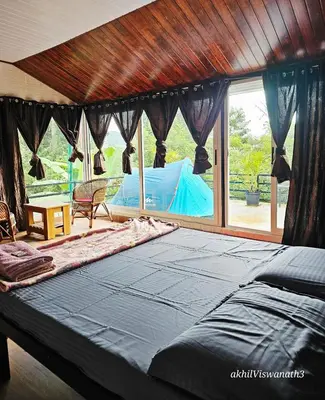 a bedroom with a large bed and a large window at Valiyattu Nest Homestay in Ambalavayal