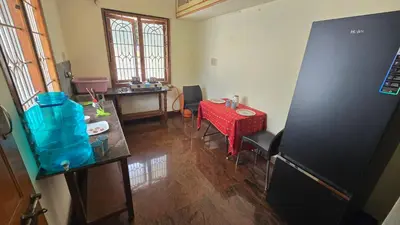 a room with a kitchen with a table and a refrigerator at Eden Garden Homestay in Mysore