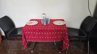 a red table with two plates and drinks on it at Eden Garden Homestay in Mysore