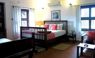 a bedroom with a bed with red and white pillows at Clayfingers Art Cottage in Trichūr