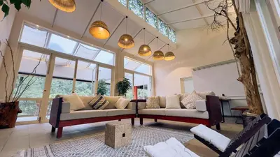 a living room with two couches and a large window at Luxury Villa in Wayanad Hills with Private Garden in Wayanad