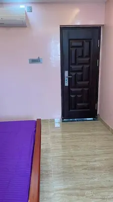 a room with a bed and a black door at Yellow Bliss - 1BK Apartment in Coimbatore