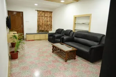 a living room with a black leather couch and a table at Aaru Residency in Coimbatore