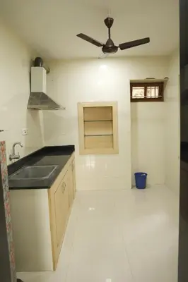 a kitchen with a sink and a ceiling fan at Aaru Residency in Coimbatore