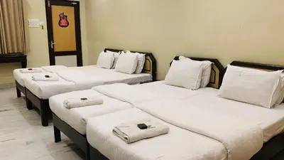 a row of four beds in a room at Hotel National Tourist Home in Trichūr