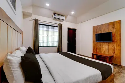 a bedroom with a large bed and a television at Hotel O OZONE Residency in Kozhikode