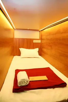 a bed in a small room with a red blanket at Stay Point Premium Capsule and Rooms in Calicut Beach in Kozhikode