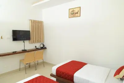 a bedroom with a bed and a desk and a television at Hotel Vishaka Paark in Coimbatore