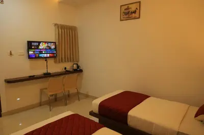 a hotel room with two beds and a flat screen tv at Hotel Vishaka Paark in Coimbatore