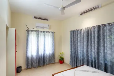 a bedroom with blue curtains and a bed and a fan at CLUB 4 Homestay in Nedumbassery