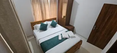 a bedroom with a bed with green and white pillows at Leela cottage in Kozhikode