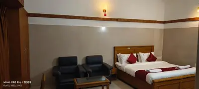 a hotel room with two beds and a chair at Skyry Hotels Gandhipuram in Coimbatore